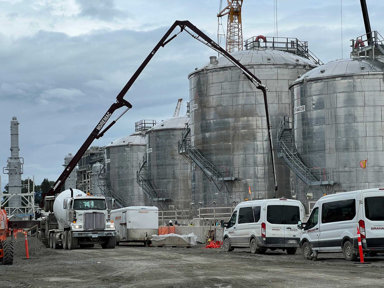 Industrial concrete pumping in action. A Noremac branded spider boom, with large metal containers in the background.