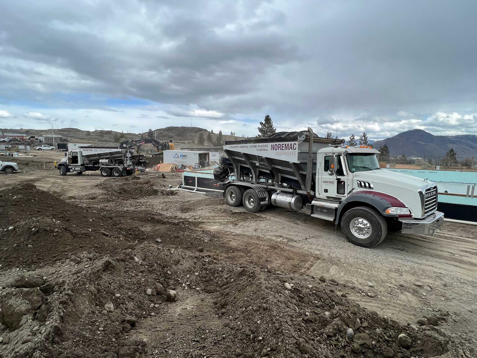 A stone slinger on a job site with the words Noremac Aggregate written on it.