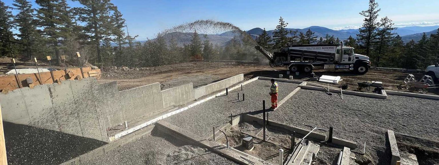 Stone slinging on a residential job site from a Noremac-branded truck.