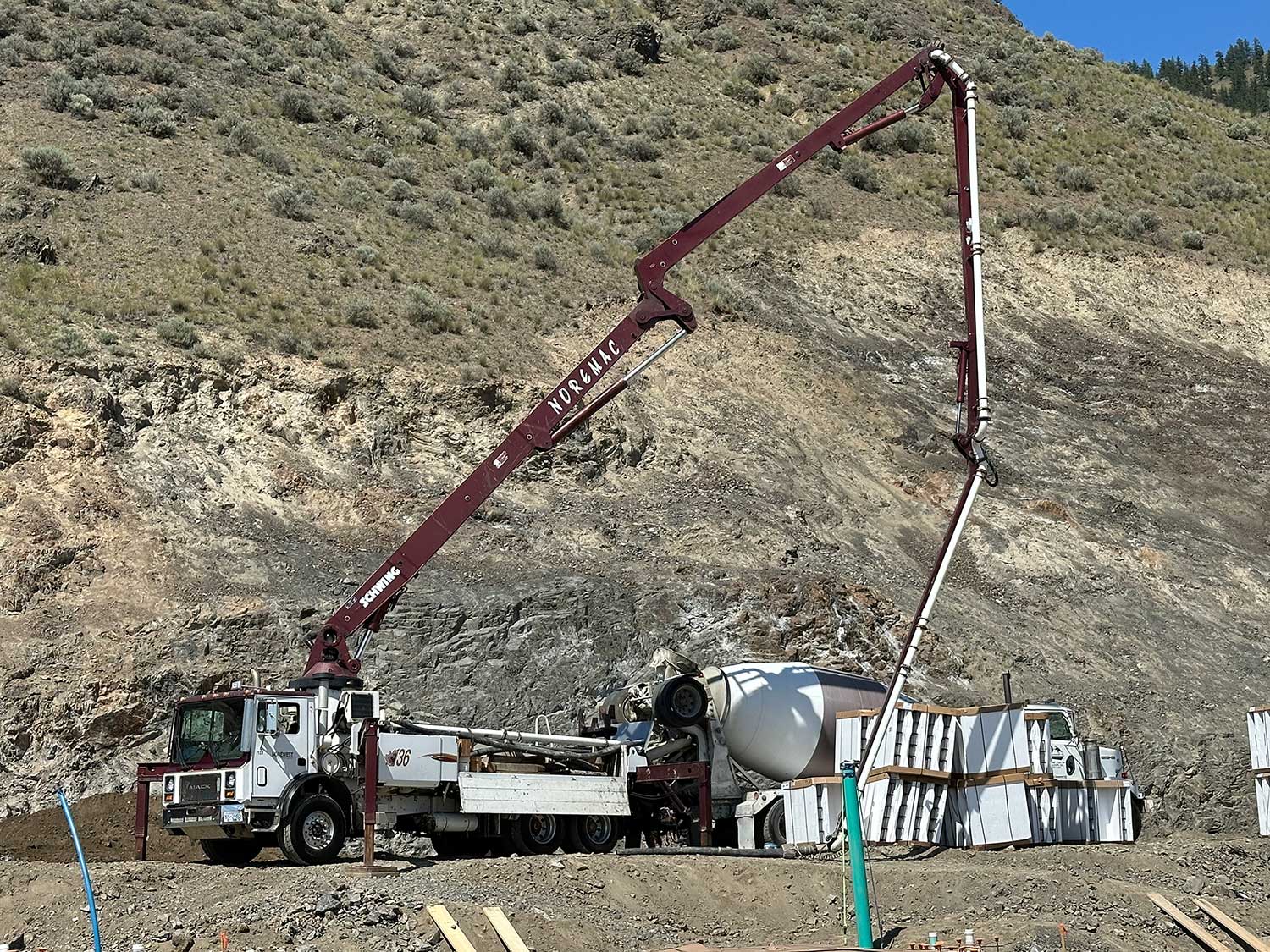 A concrete mixer in use with a Noremac branded spider boom.