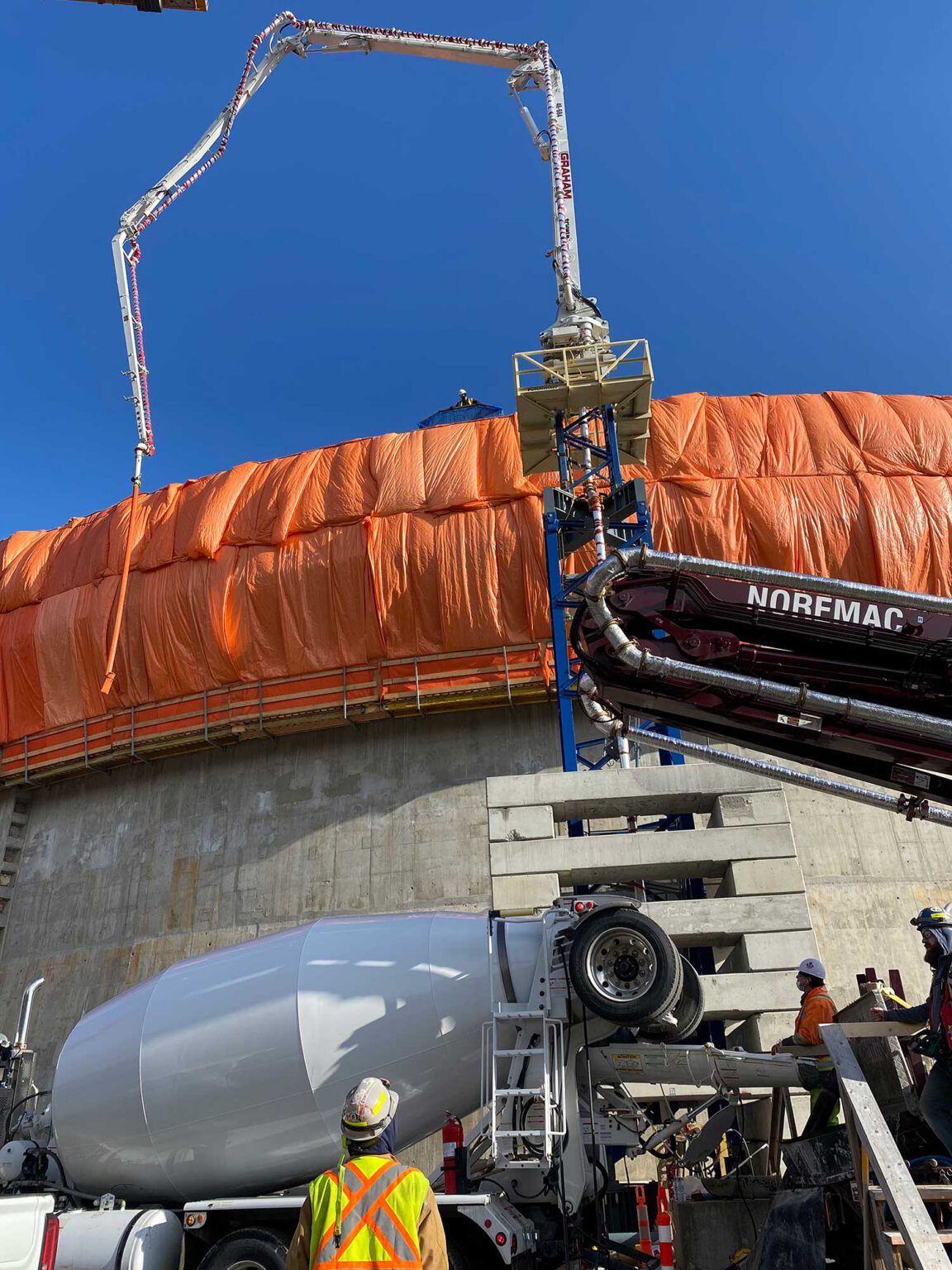 A placing boom in use with a concrete mixer in the foreground.