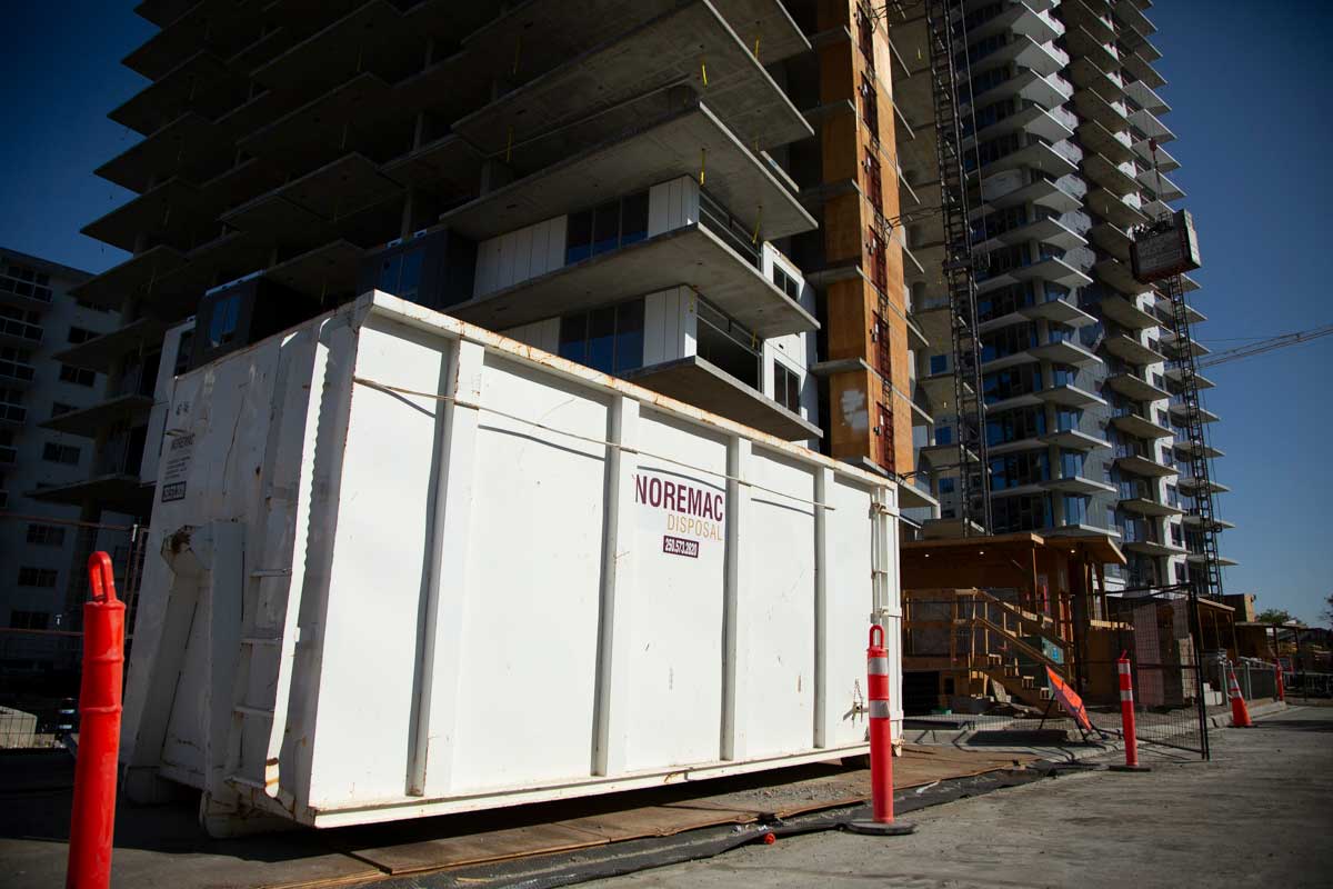 A Noremac disposal bin on the construction site of an apartment building.