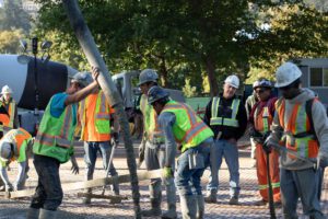 Concrete pumping workers with a line pump in use.