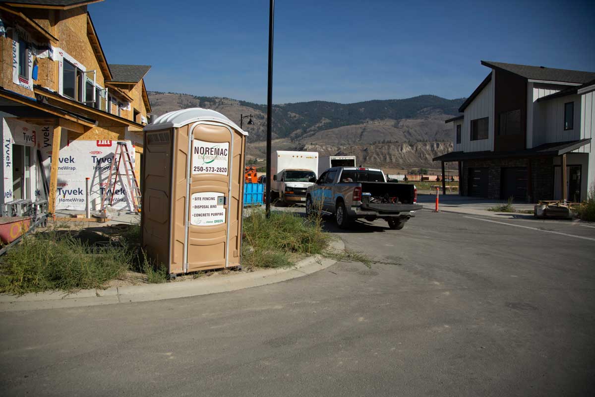 A Noremac portable toilet on a residential construction site.