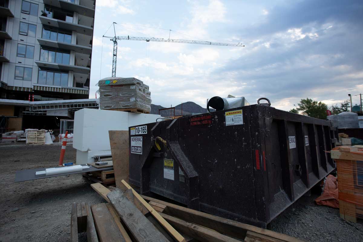 A Noremac branded disposal bin in the construction site of an apartment building.