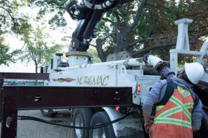 Noremac concrete pumping equipment in action with a concrete pumping worker in the foreground.