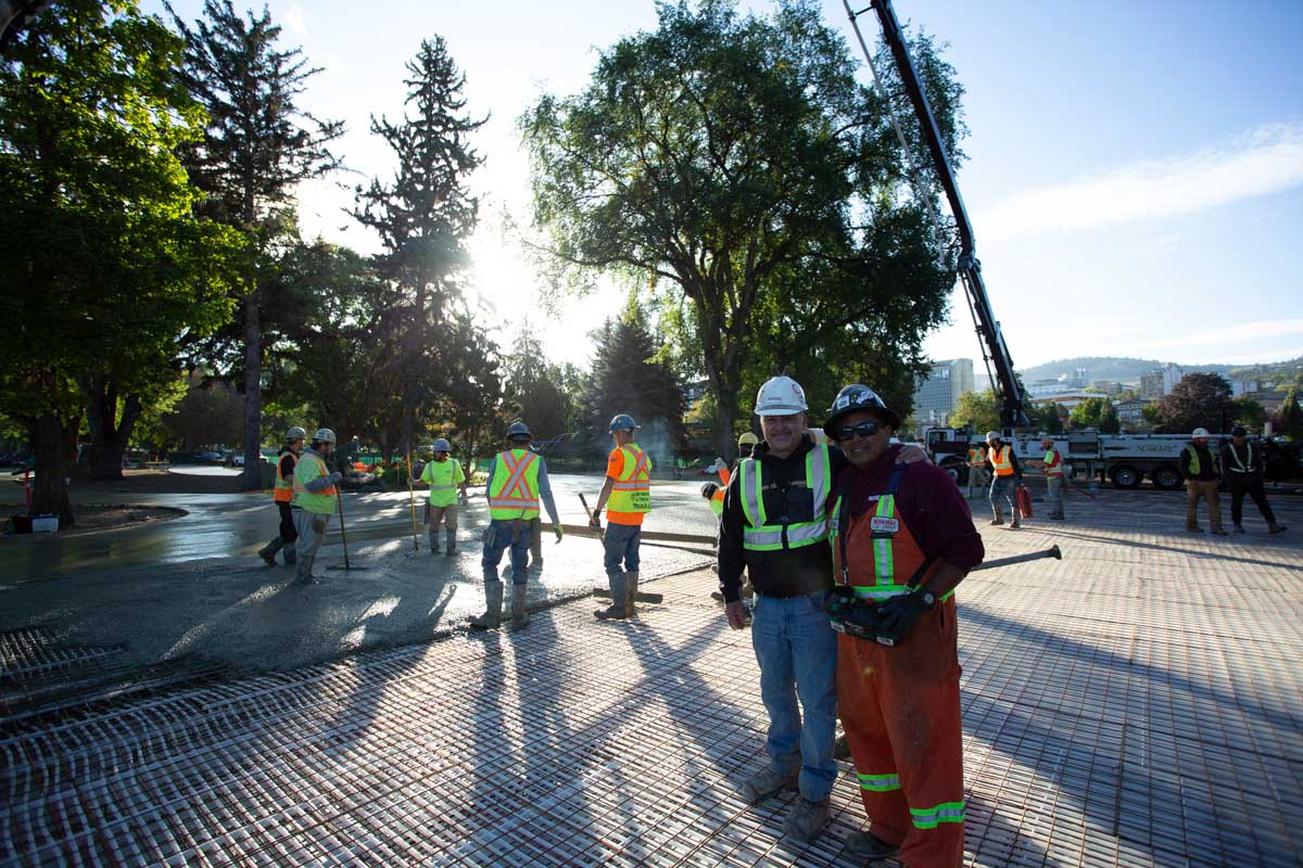 A team of happy Noremac workers on a job site, pouring concrete on a sunny day.
